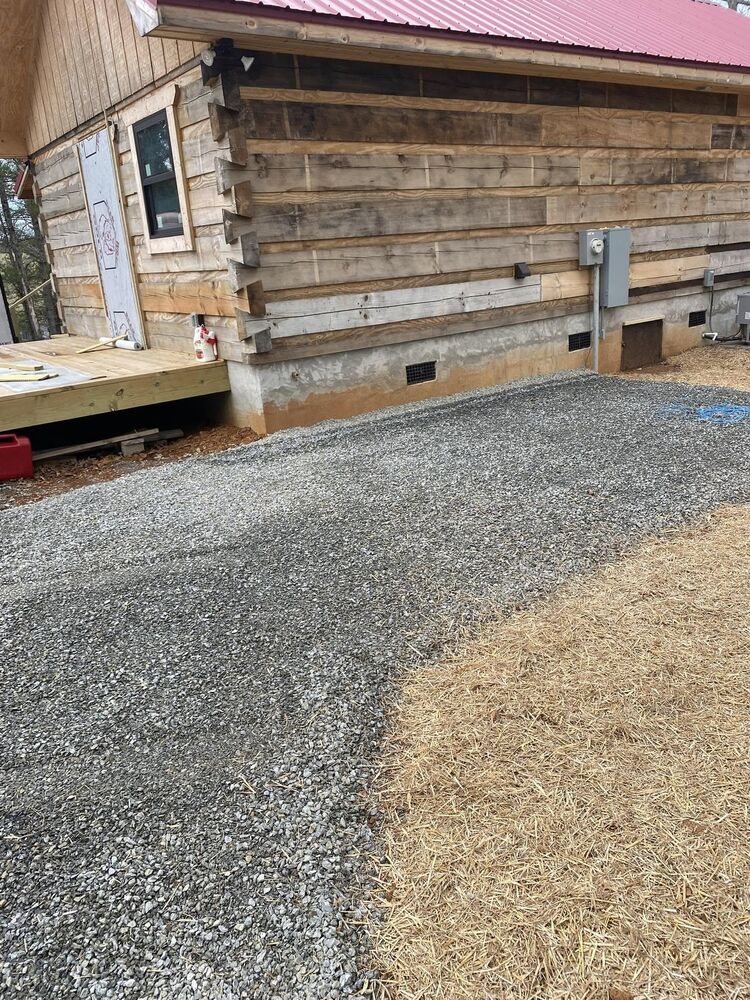 A fresh gravel driveway running beside a log cabin