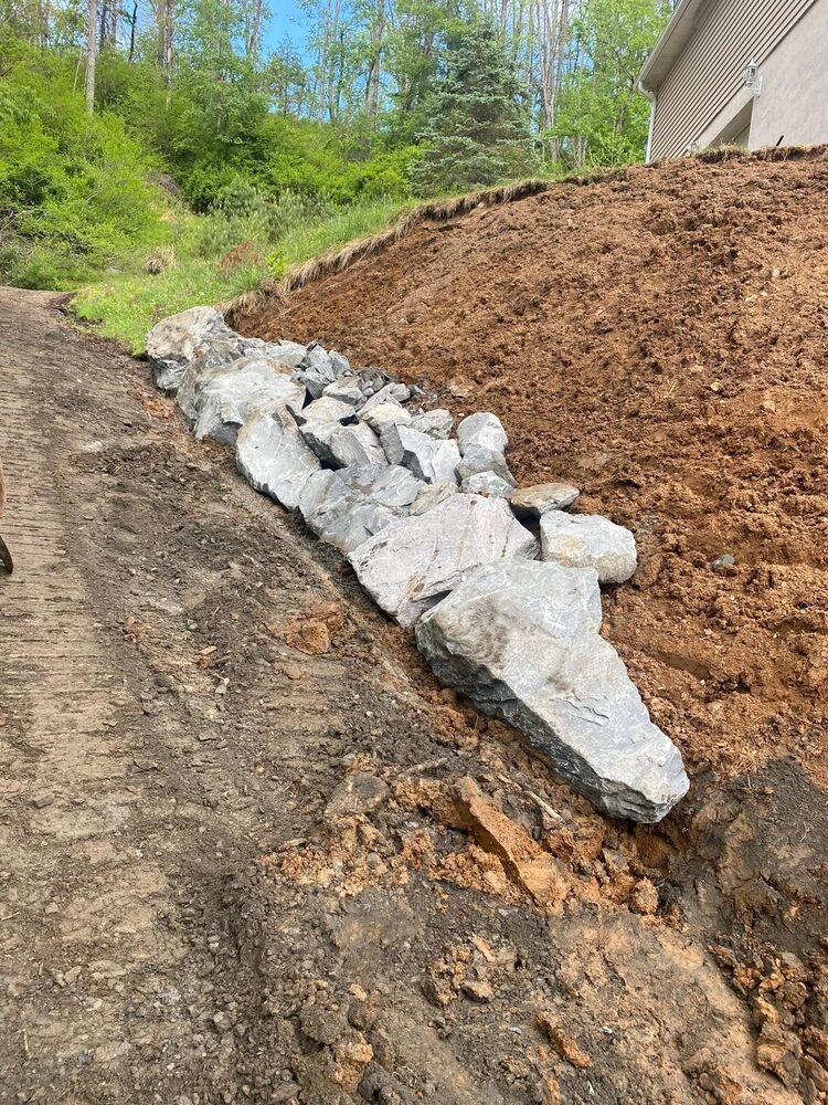 A driveway cut into a hillside with a stone riprap edge holding back the bank